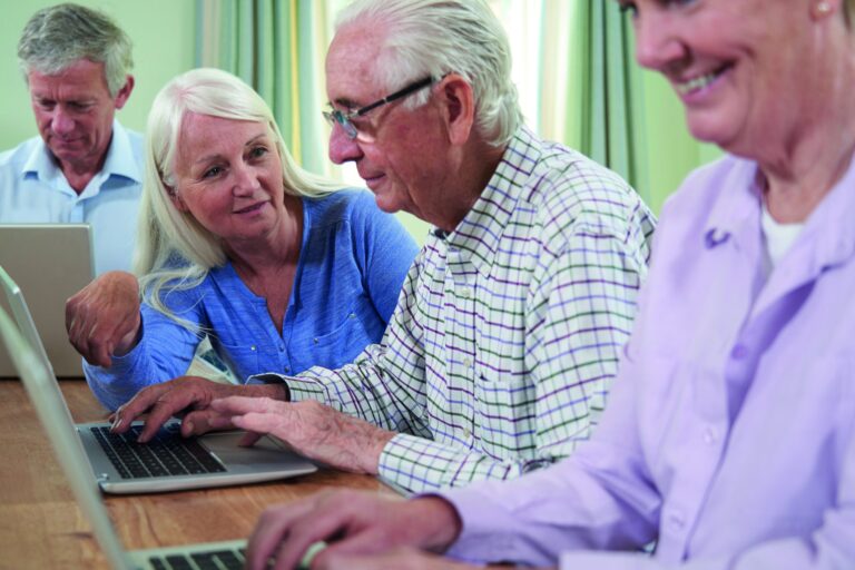 Teacher With Senior Students In Computing Adult Education Class