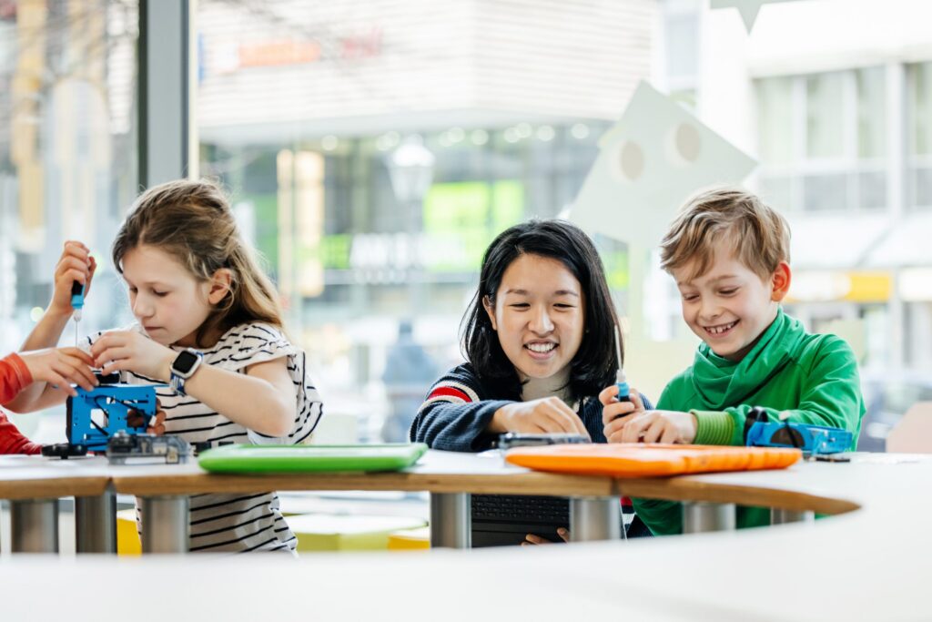 Teacher Helping Young Children During Tech Workshop